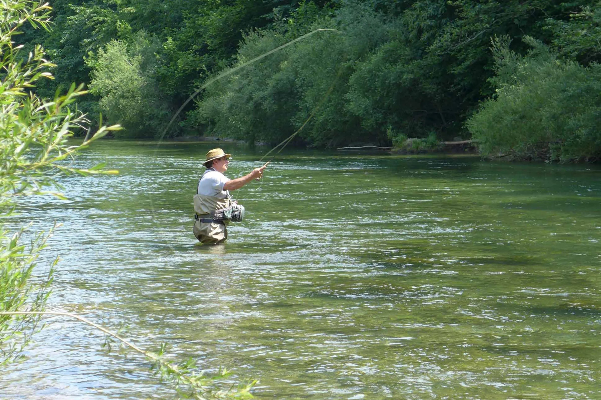 A man fly casting in an open river