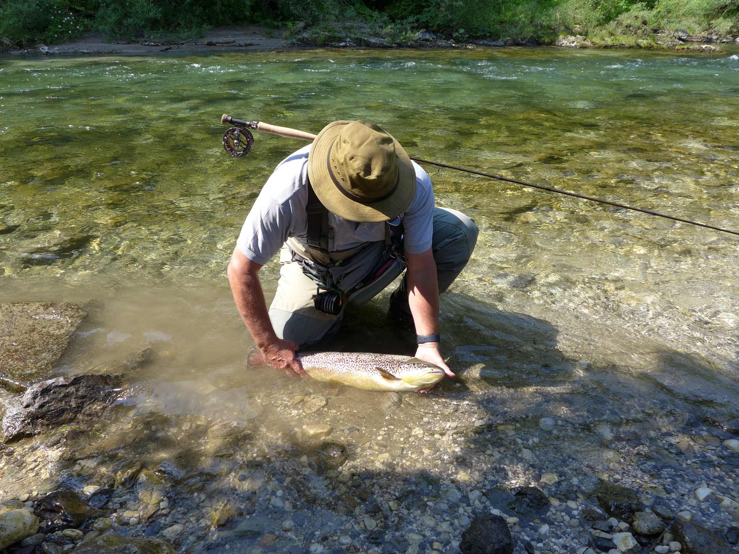 Man holding fish he has just caught in river