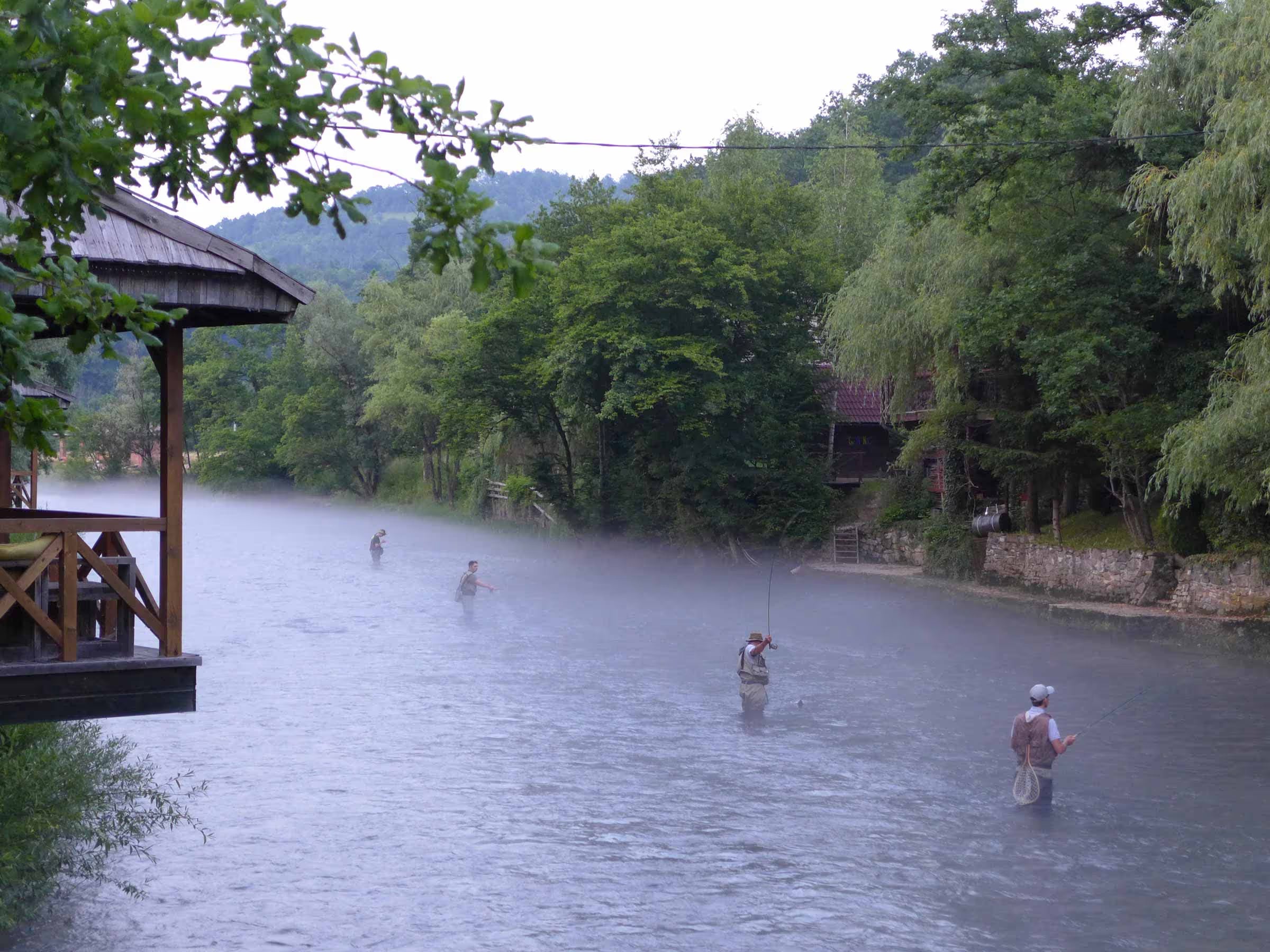 A high level photo of several anglers fly fishing along a river