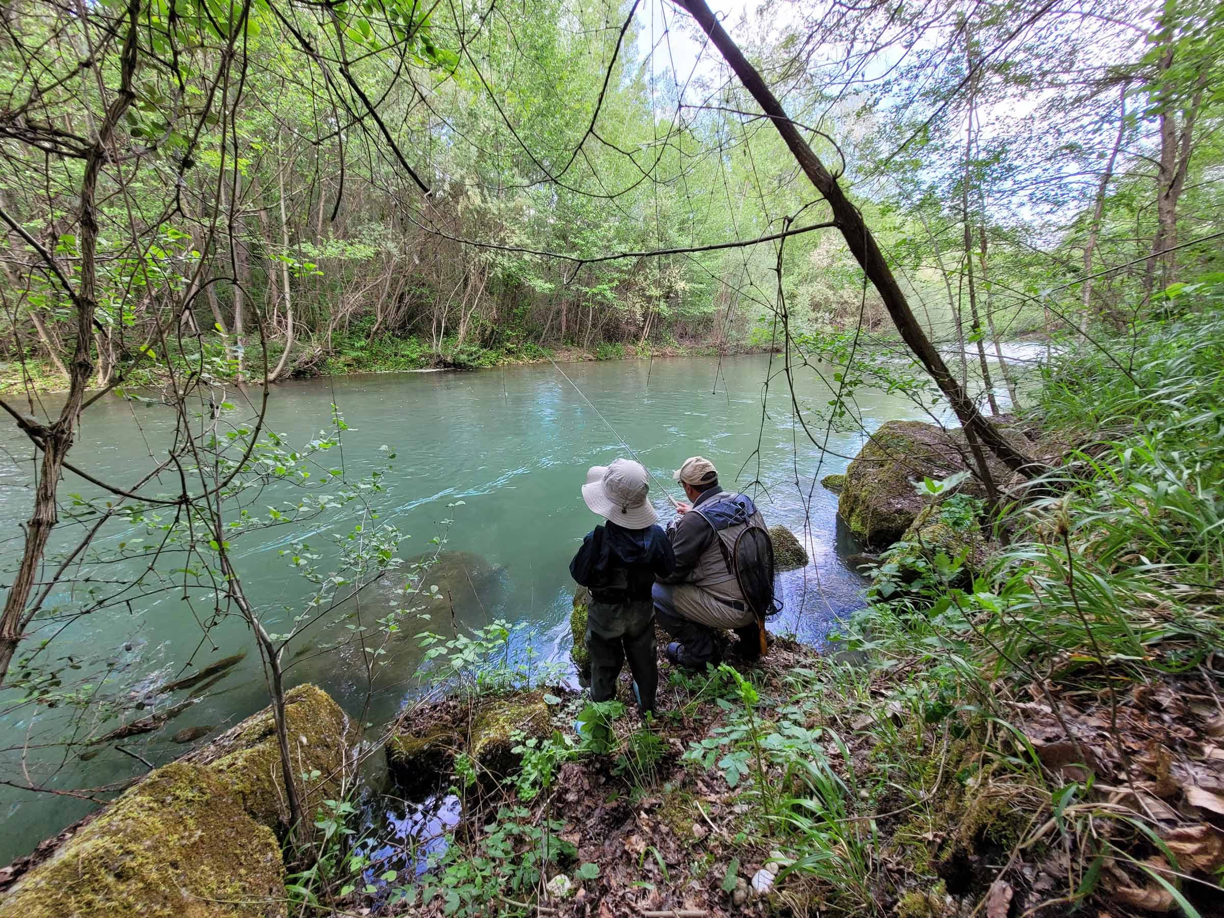 Father and son fishing on a river bank